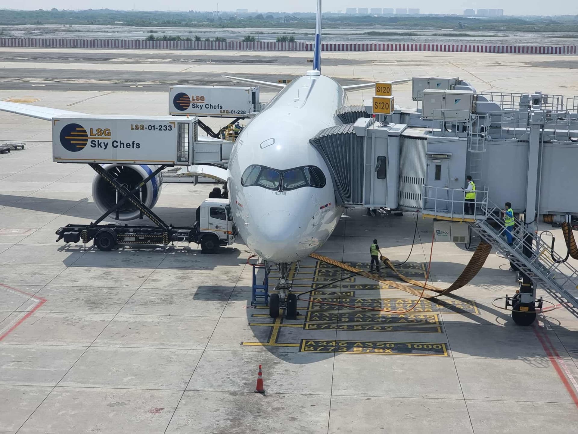 Airliner parked at a gate with ground crew on the apron